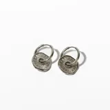 Aros tipo argolla de acero plateado con dije circular calado con diseño de rayos.