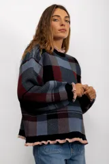 Sweater de punto con diseño de cuadros tartán en escala XL, en tonos azul, negro y bordó. Presenta un corte oversize, cuello redondo y terminaciones con volados en color rosado en el cuello, puños y ruedo.