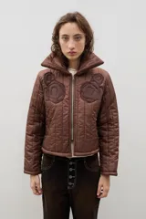 Campera crop acolchada color marrón, con cuello alto, cierre frontal y apliques de flores en el pecho. Presenta un diseño capitoneado y forro interior.