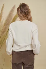 Buzo de punto color negro con cuello redondo, mangas largas y detalle de mandala tejido en color crema en el frente.