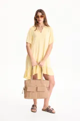 Bolso tipo tote color beige de poliuretano, con dos bolsillos frontales con solapa, asas dobles para el hombro y cordones ajustables en los laterales.