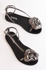Sandalias bajas color cuero con tiras finas y aplique de flor dorada.