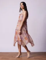 Vestido midi de gasa estampada con motivos geométricos en tonos naranja, lila y beige. Tiene breteles finos regulables, escote en V con volados y falda asimétrica con volados.