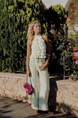 Bolso de hombro de material efecto acharolado en color fucsia, con diseño alargado, doble compartimento exterior y detalle de lazos en los laterales. Cuenta con doble asa de hombro ajustable y cierre superior con cremallera.