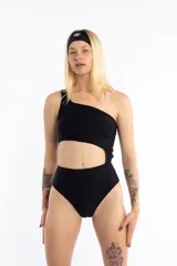 Malla enteriza negra con diseño irregular de un solo hombro y aberturas laterales en la cintura.