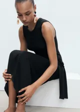 Vestido midi negro sin mangas, con cuello redondo, tirantes anchos, diseño recto y detalle de nudo en la cintura.