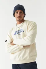 Buzo color crema de felpa con cuello redondo y lettering estampado en azul con la frase "Always Grateful".