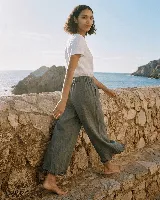 Pantalón capri de lino color verde militar, con cintura elástica y detalles de flecos en los tobillos.