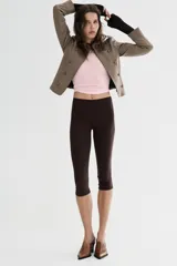 Blazer entallada color beige con rayas verticales finas, cuello redondo y manga larga. Presenta trabillas en los hombros y botones metálicos decorativos en el frente. Cierre frontal con cremallera y forro interior.