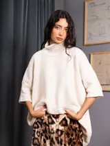 Polerón negro de tejido de punto con cuello alto, diseño oversized, mangas 3/4 y corte asimétrico más largo en la parte posterior.