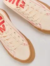 Championes bajos color crema con pespuntes rojos, capellada de tela canvas y plataforma de goma color caramelo de 4 cm de altura.