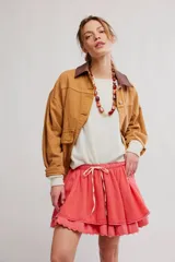 Minifalda color coral, de tela liviana con dos capas de volados, cintura elastizada con cordón ajustable y borde festoneado con puntilla.