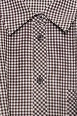 Camisa corta de manga larga con cuello solapa, confeccionada en tela con estampado de cuadros vichy en color bordó y blanco. Presenta un bolsillo delantero de plastrón, cierre frontal con botones y bajo abullonado con elástico interior.
