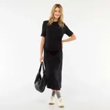 Vestido midi negro de manga corta, con cuello redondo y detalle de torsión en la cintura que genera un drapeado lateral. Presenta un tajo lateral en el ruedo.