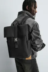 Mochila de diseño minimalista en acabado engomado color negro. Cuenta con compartimento principal con cierre de solapa y hebilla de liberación rápida, bolsillo frontal con cierre, compartimento interno para dispositivos electrónicos y espalda acolchada con banda de sujeción para equipaje.