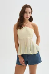 Top halter color amarillo claro, con escote strapless y detalle de argolla en el cuello, confeccionado en viscosa con diseño holgado y acabado fluido.