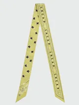 Pañuelo tipo bandana de seda, color amarillo con estampado gráfico y letras en negro. Diseño cuadrado con bordes definidos.