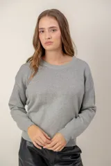 Sweater de punto con cuello redondo y mangas largas, presenta un diseño con efecto degradado metalizado en la parte superior y hombros.