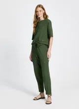 Pantalón jogger verde de tejido de punto con corte recto, cintura con trabillas y cordón ajustable con puntas de madera. Presenta bolsillos laterales con solapa y pespuntes.