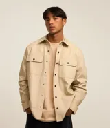 Camisa manga larga de sarga en color verde militar, con cuello inglés, cierre frontal de botones negros y dos bolsillos con solapa en el pecho.