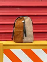 Mochila de cuero sintético color marrón y beige con textura símil cocodrilo, cierre superior con doble cremallera y tiradores de cuero, bolsillo vertical frontal con cremallera, bolsillo trasero oculto con cremallera, interior forrado con bolsillo con cremallera y correas regulables.