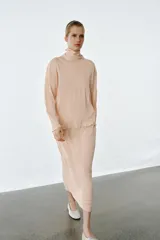 Falda midi de punto color rosado con efecto arrugado, cintura elástica y detalle de volados en la parte superior.