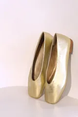 Ballerinas doradas con punta redondeada y suela plana color madera.