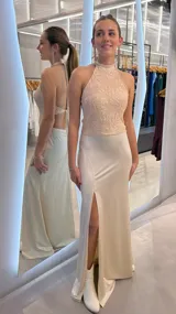 Vestido largo beige, con cuerpo de cuello halter bordado con motivos florales y falda fluida con abertura frontal en la pierna.