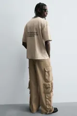 Pantalón cargo de denim lavado negro, corte relajado y tiro medio. Presenta múltiples bolsillos cargo con solapa y detalle de cierre en las perneras, además de bolsillos de vivo traseros. El bajo es ajustable con trabilla.