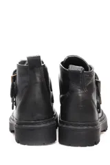 Botín negro de cuero con caña corta, suela track y ajuste con hebillas doradas.