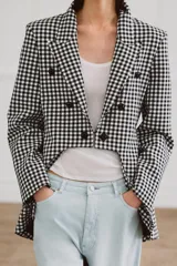 Blazer Zara Woman Collection de corte asimétrico con estampado de cuadros vichy en blanco y negro. Presenta cuello solapa, cierre frontal con botones y un diseño de bajo irregular con abertura central.