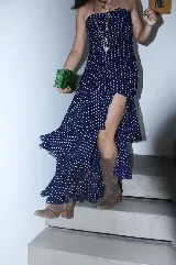 Vestido largo negro strapless de encaje con frunces en el torso, falda asimétrica en capas con volados y breteles removibles.