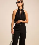 Pantalón de corte recto para mujer, confeccionado en jacquard negro con textura. Cuenta con cintura elástica integrada, hebilla decorativa frontal y cierre lateral.