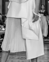 Falda asimétrica de tiro alto color blanco, confeccionada en seda triple. En la delantera posee tres tablones escalonados y una pieza en gasa translúcida plisada, que poco a poco van definiendo el largo irregular del diseño.