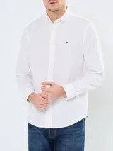 Camisa blanca de popelina de algodón flexible, con cuello abotonado, cierre frontal con botones y puños abotonados. Tiene logo de Tommy Hilfiger bordado en el pecho.