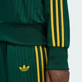 Campera deportiva Adidas Firebird de color verde oscuro con textura de rayas de tiza y detalles en amarillo, incluyendo las clásicas tres tiras en las mangas y el logo del trifolio bordado en el pecho. Cuenta con cuello alto, cierre frontal completo y bolsillos laterales.