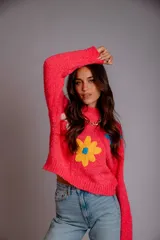 Buzo de punto color fucsia, con cuello redondo, manga larga y bordado de flores en amarillo y azul en el frente.