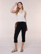Pantalón capri de jean azul con calce ajustado, tiro alto, cinco bolsillos, cierre frontal con botón y pequeños tajos en los ruedos.
