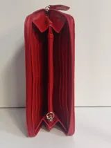 Billetera rectangular con cierre perimetral, confeccionada en cuero con textura de reptil. Cuenta con múltiples compartimentos internos para tarjetas, documentos y billetes, además de un bolsillo interior con cierre para monedas.