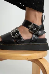 Sandalias negras de cuero con plataforma y hebillas plateadas.