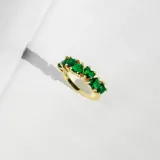 Anillo dorado con detalle de cristales en forma de corazón color verde esmeralda.