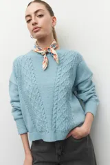 Sweater de tejido tramado color celeste claro, con diseño de trenzas en el frente y puños elastizados.