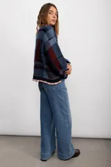 Sweater de punto con diseño de cuadros escoceses en tonos marrones y beige. Presenta un corte oversize, cuello redondo y terminaciones con volados en el cuello y los puños.
