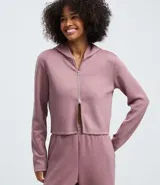 Campera corta con capucha fija, cierre frontal con cremallera y mangas largas, confeccionada en tejido modal con acabado satinado.