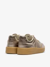 Championes Veja modelo V-90, con diseño de cuero metalizado en tono cobre. Presentan el logo de la marca en el lateral, cordones al tono y una suela de goma color caramelo.