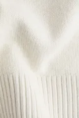 Buzo de punto oversized con cuello tortuga acanalado y abertura en la nuca. Presenta mangas raglán con costuras decorativas y terminaciones acanaladas en puños y bajo.
