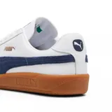 Championes Puma modelo Army Trainer, de diseño retro en color blanco con detalles en verde oscuro y suela de goma color caramelo. Presenta refuerzos de gamuza en la puntera y el logo de la marca en dorado en el lateral.