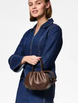 Bolso tipo saco o 'balloon' de efecto cuero color marrón oscuro (Chicory Coffee) con asa superior y correa ajustable para llevar al hombro o cruzado. Presenta herrajes plateados y cierre magnético.