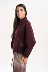 Campera bomber de paño color bordó, con cuello alto, cierre frontal metálico y mangas amplias con hombro caído. Presenta un calce relajado y silueta levemente corta con ajuste inferior.