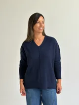 Sweater de punto en color azul marino, con escote en V, manga larga con puños acanalados y costura central vertical en el frente.
